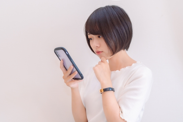 仮装メイクを考えながらスマートフォンを見る女性